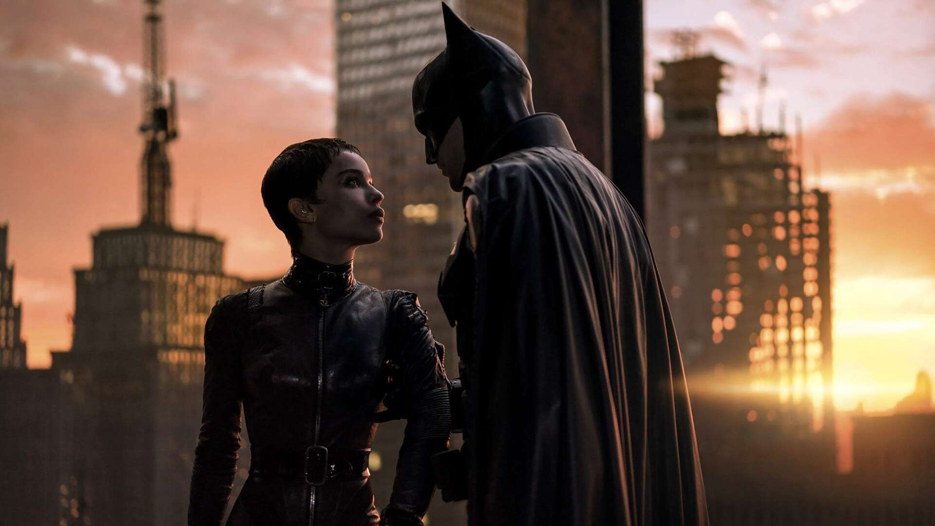 Batman and Catwoman in a scene of the movie The Batman (2022). On the background, Gotham City at sunset.