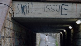 A frame from the movie Skill Issue (2024). The bridge has a graffiti on it. It says Skill Issue.